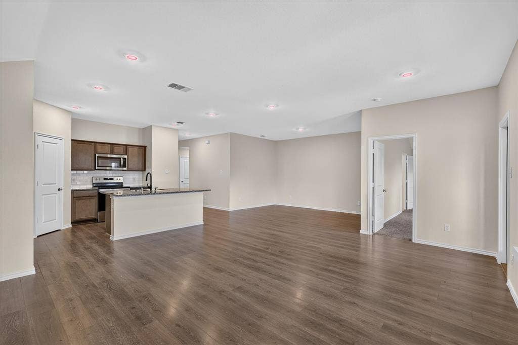 114 Real Quiet Lane, Caddo Mills, TX 75135 Open-concept living space featuring wood-finish flooring, recessed lighting, a kitchen island with stone countertop, and dark-finish cabinetry