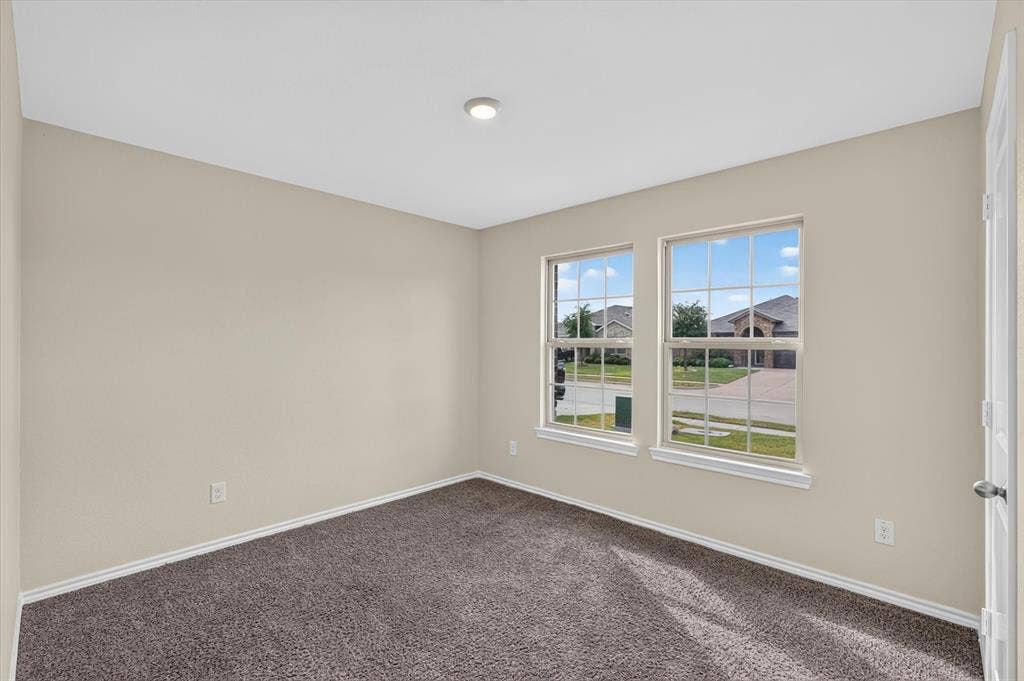 114 Real Quiet Lane, Caddo Mills, TX 75135 Neutral-toned interior room featuring wall-to-wall carpeting, dual windows with grid detailing, and a flush-mount ceiling light fixture