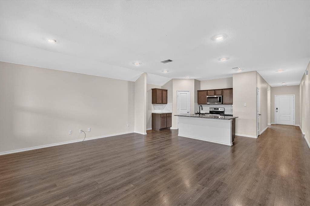 114 Real Quiet Lane, Caddo Mills, TX 75135 Open-concept space featuring wood-finish flooring, recessed lighting, a kitchen island with stone-finish countertops, dark cabinetry, and stainless steel built-in appliances