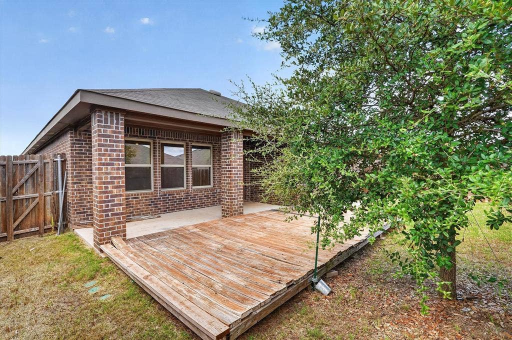 114 Real Quiet Lane, Caddo Mills, TX 75135 Rear exterior featuring a brick facade, covered patio with brick columns, and wooden deck