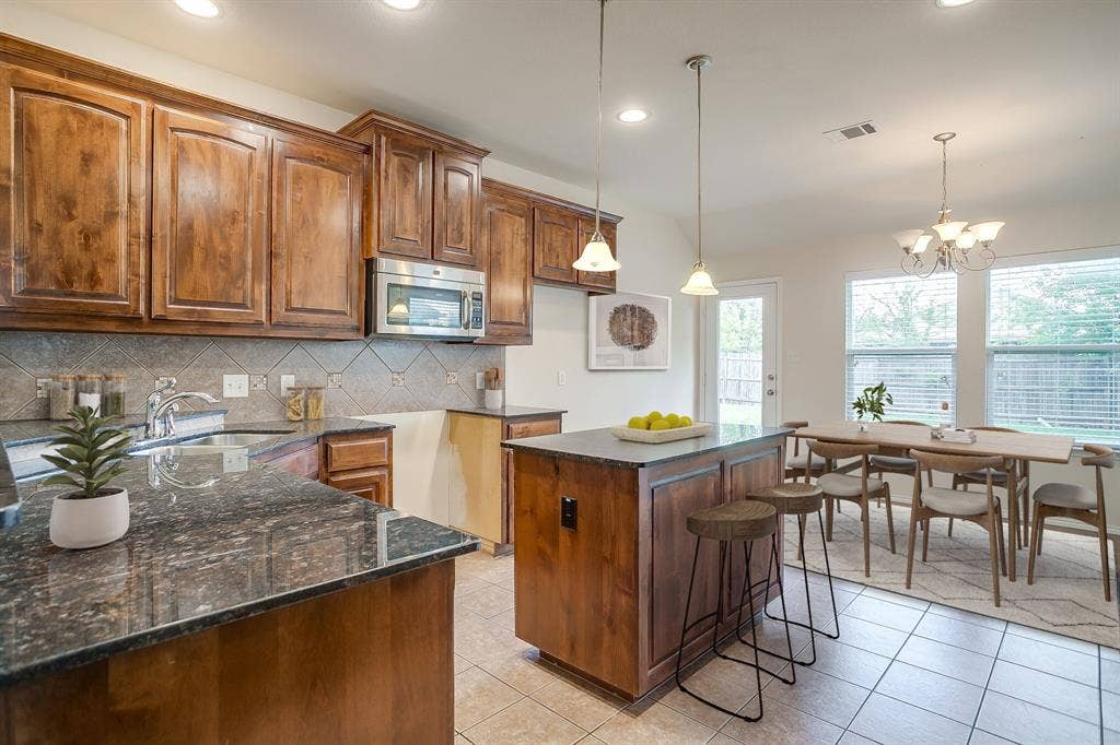 Kitchen featuring stained wood cabinetry, stone-surface countertops, central island, decorative tile backsplash, and recessed lighting