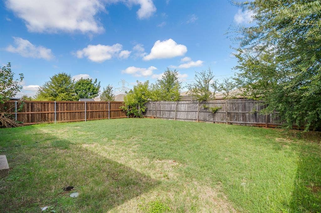 Backyard featuring an expansive lawn, full-perimeter wood privacy fencing, and mature trees