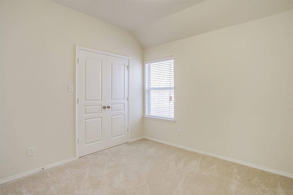 Room featuring neutral-toned carpeting, off-white wall finishes, a single-pane window with horizontal blinds, and double-panel closet doors with spherical knobs