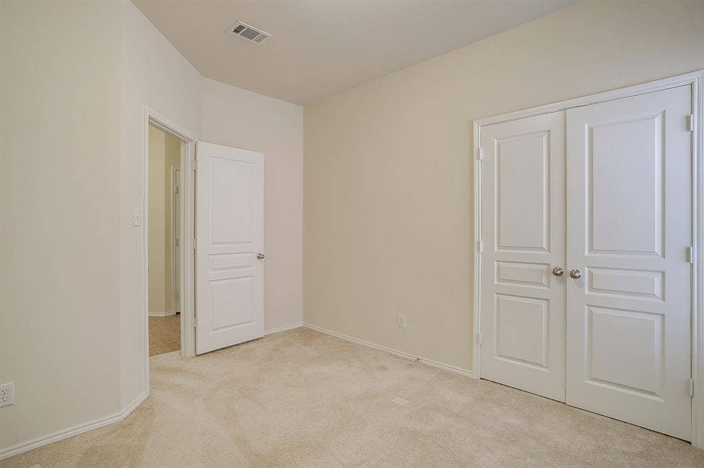 Neutral wall tones featuring carpeting, panelled doors, and double-door closet entry