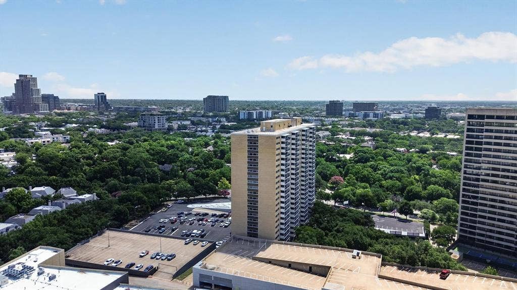High-rise urban landscape featuring an expansive cityscape, mature tree canopy, and multi-level parking structures