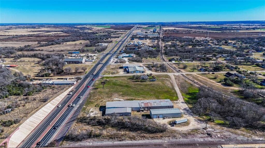 110 1st Street, McGregor, TX 76657 Aerial perspective of a multi-structure commercial site featuring metal-siding construction, gravel-surfaced driveways, and direct frontage on a multi-lane highway