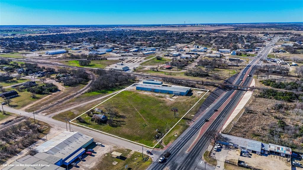 110 1st Street, McGregor, TX 76657 Aerial perspective of expansive acreage featuring a detached warehouse structure, road frontage, and open terrain