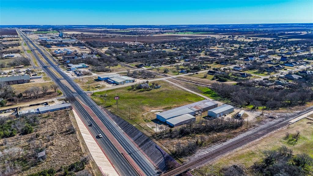 110 1st Street, McGregor, TX 76657 Aerial perspective of the acreage featuring metal-sided structures, expansive open terrain, and direct frontage to a multi-lane highway