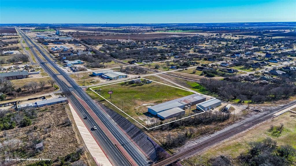 110 1st Street, McGregor, TX 76657 Expansive acreage featuring prominent highway frontage, multiple metal-clad structures, and open-land utility