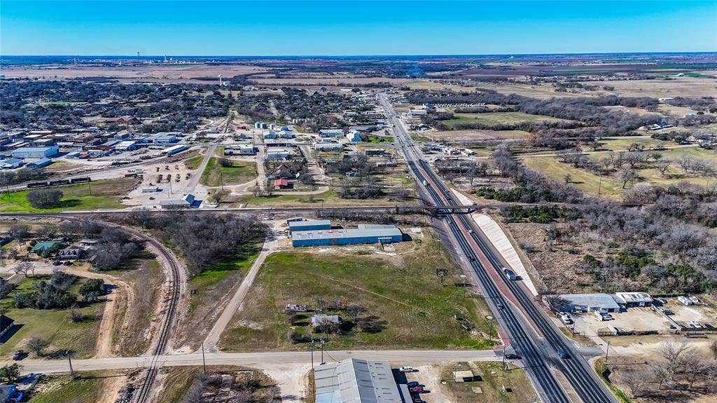 110 1st Street, McGregor, TX 76657 Aerial perspective featuring open land, proximity to a multi-lane highway, rail lines, and surrounding commercial infrastructure