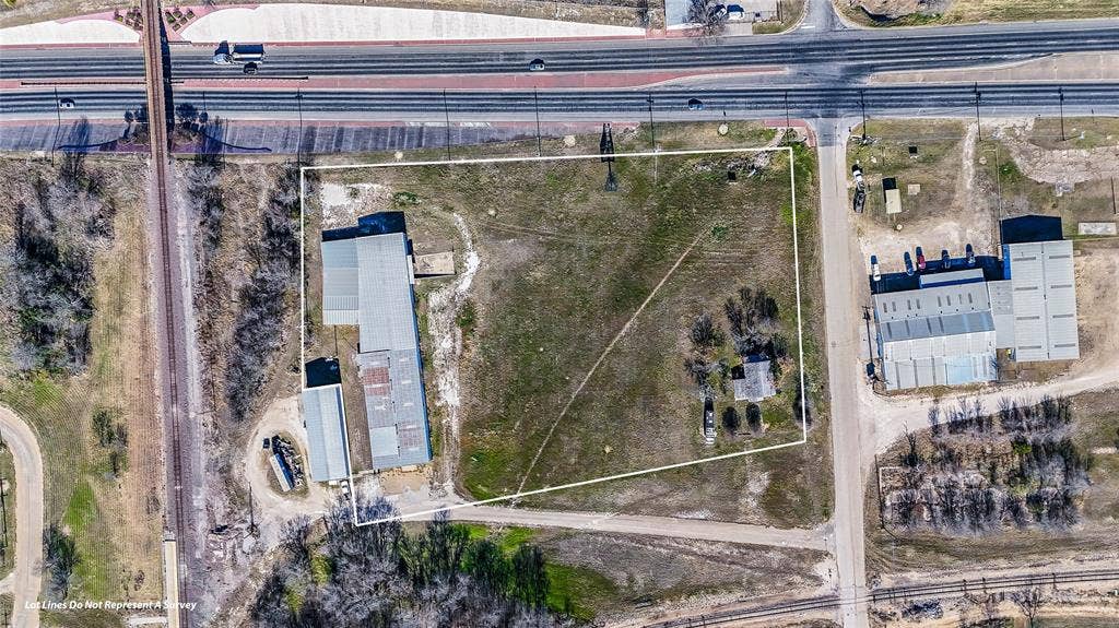110 1st Street, McGregor, TX 76657 Expansive parcel of land featuring metal-roofed industrial structures, gravel surface areas, and direct proximity to major thoroughfares