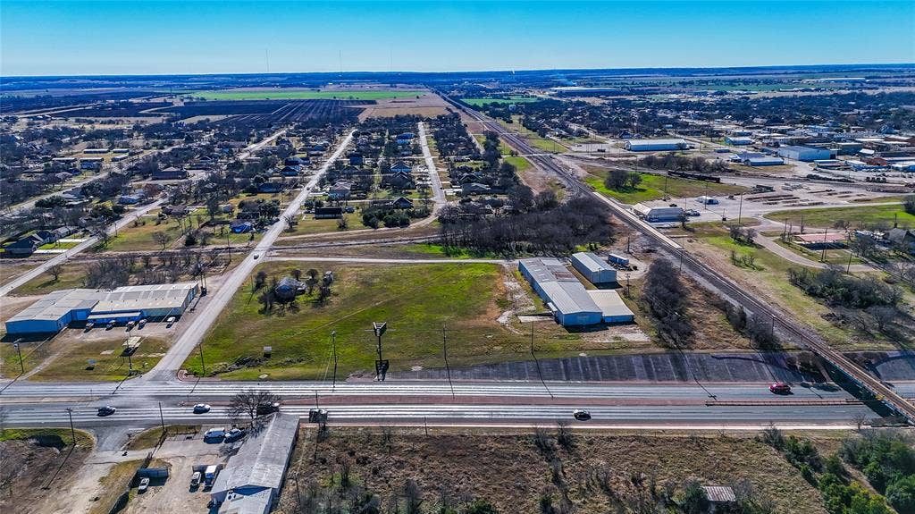 110 1st Street, McGregor, TX 76657 Aerial view of expansive land parcel featuring paved street frontage, direct proximity to railway lines, existing industrial-style structures, and open acreage
