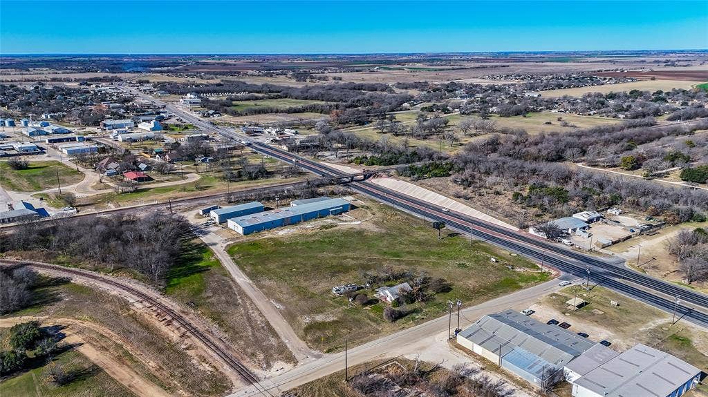 110 1st Street, McGregor, TX 76657 Aerial perspective featuring expansive land acreage with dual-road frontage, industrial-style structures, and direct rail line access