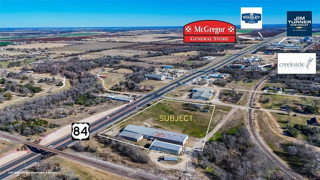 110 1st Street, McGregor, TX 76657 Aerial perspective of a property featuring extensive open acreage, direct frontage on Highway 84, and a metal-clad industrial structure