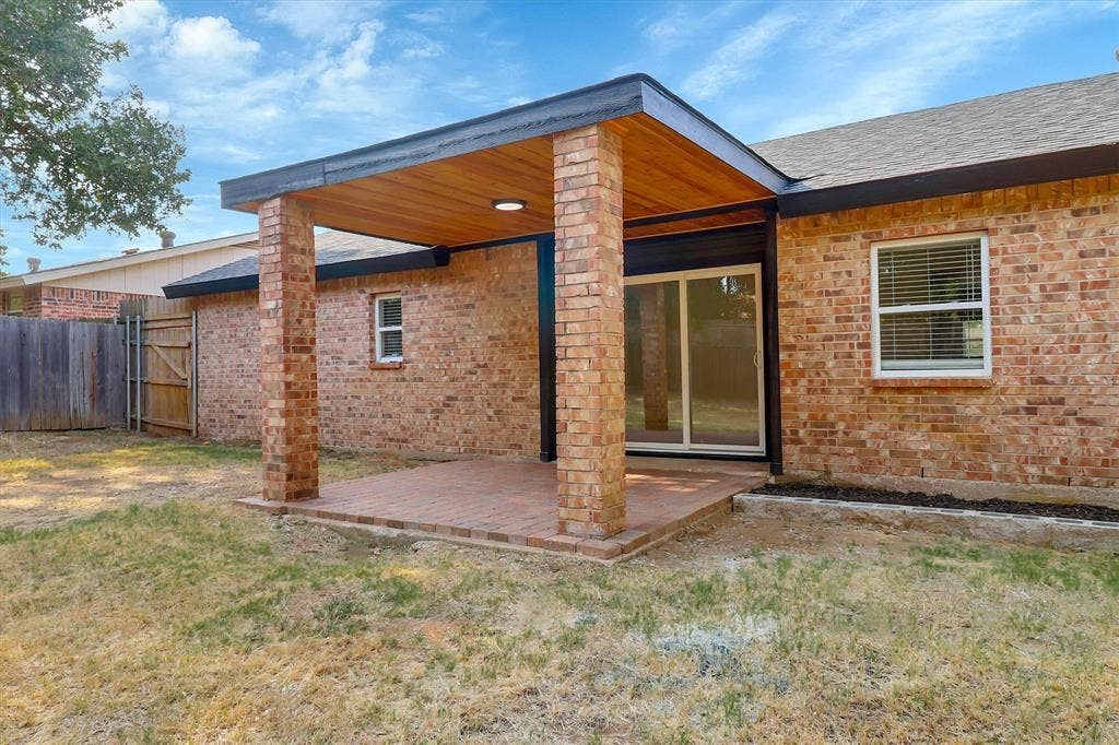 1913 Sandra Kay Lane, Arlington, TX 76015 Covered brick patio featuring a wood-paneled ceiling, structural brick columns, and a sliding glass door entry