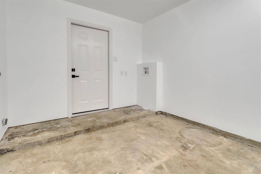 1913 Sandra Kay Lane, Arlington, TX 76015 Utility area featuring a raised concrete platform, white-painted walls, an exterior-grade entry door with matte black hardware, and dedicated plumbing connections