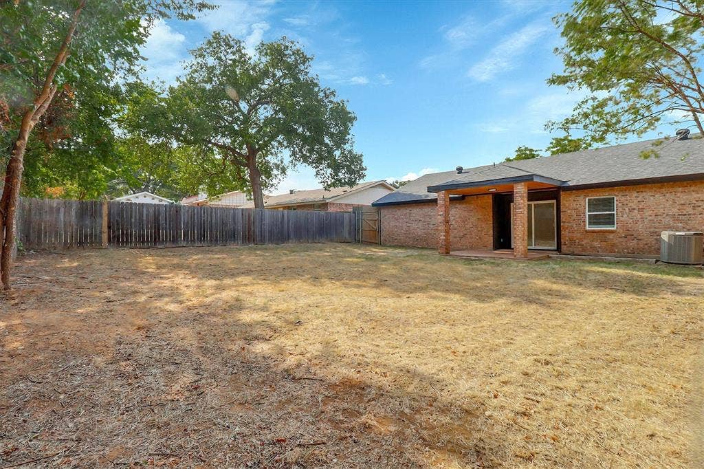 1913 Sandra Kay Lane, Arlington, TX 76015 Backyard featuring brick exterior walls, a covered patio with brick support columns, and full wood privacy fencing