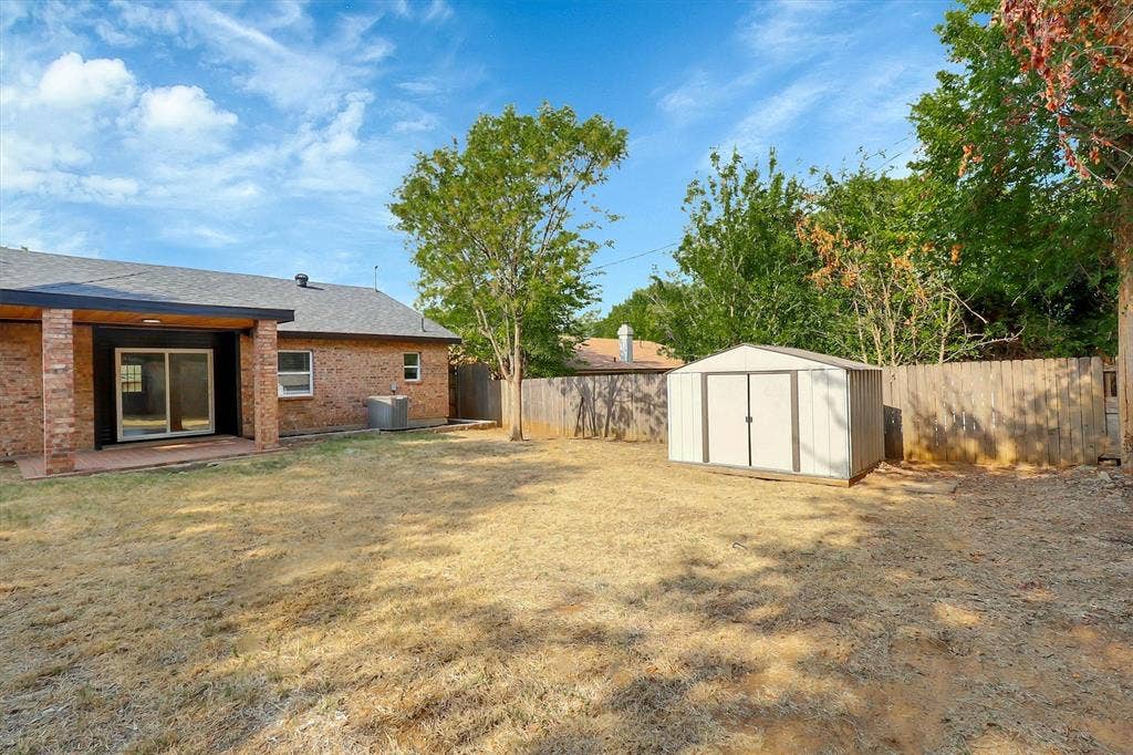 1913 Sandra Kay Lane, Arlington, TX 76015 Rear brick exterior featuring a covered patio, detached storage shed, and perimeter wood fencing