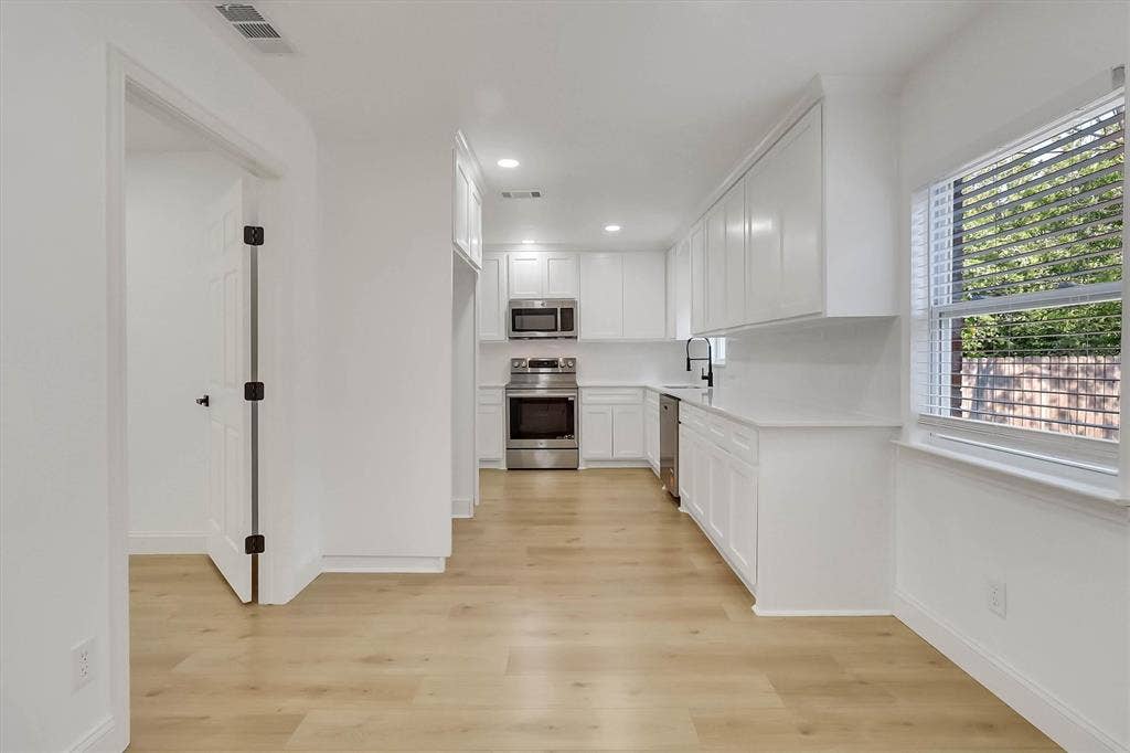 1913 Sandra Kay Lane, Arlington, TX 76015 Kitchen featuring white shaker cabinetry, stainless steel appliances, light wood-finish flooring, quartz countertops, and a matte black faucet