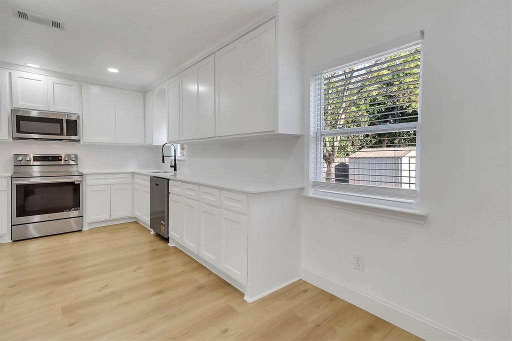 1913 Sandra Kay Lane, Arlington, TX 76015 Kitchen featuring white shaker-style cabinetry, stainless steel appliances, light-toned wood-finish flooring, solid-surface countertops, and a gooseneck faucet