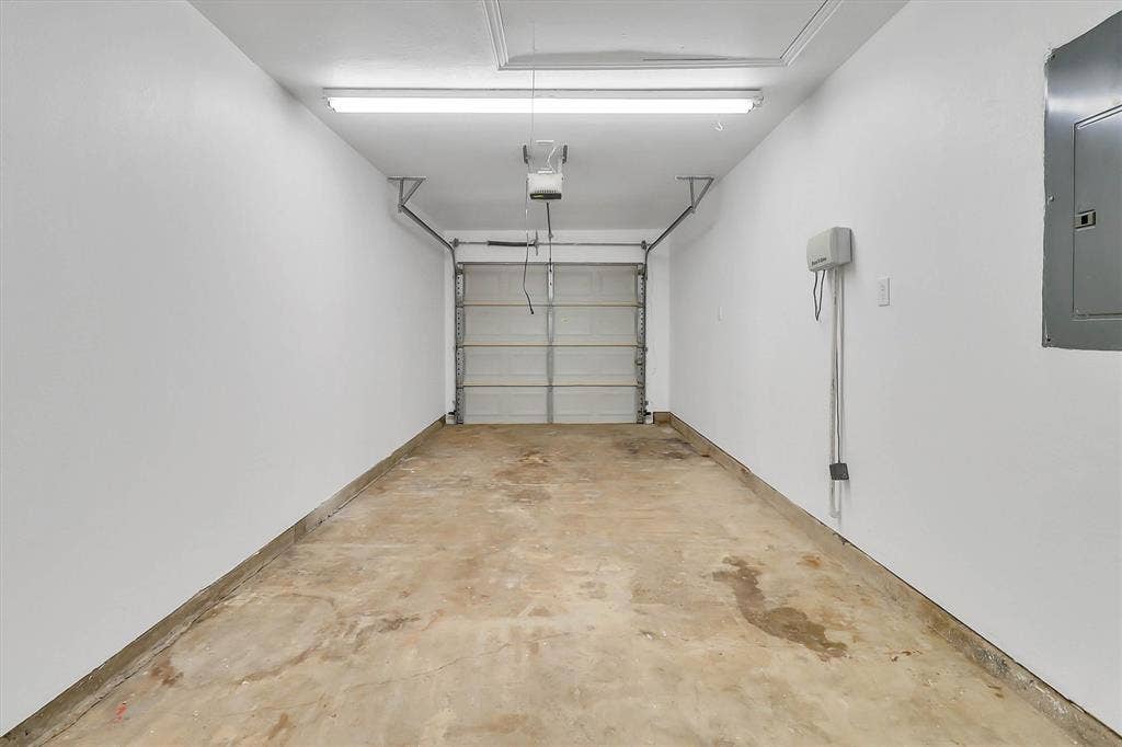 1913 Sandra Kay Lane, Arlington, TX 76015 Single-car garage featuring a sectional overhead door, finished walls, fluorescent ceiling lighting, and an integrated electrical service panel