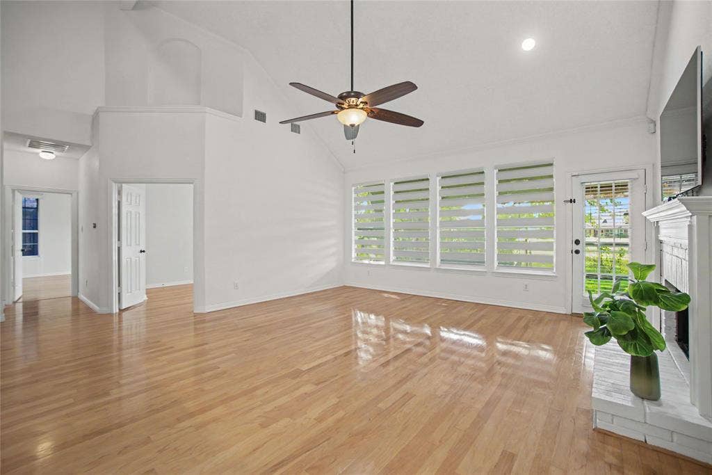 A spacious family room has tall panel windows and a mantled corner fireplace. On the left, see the view of the Primary and 2nd Bd.