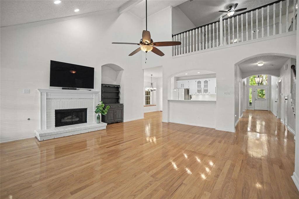 A spacious family room has tall panel windows and a mantled corner fireplace.