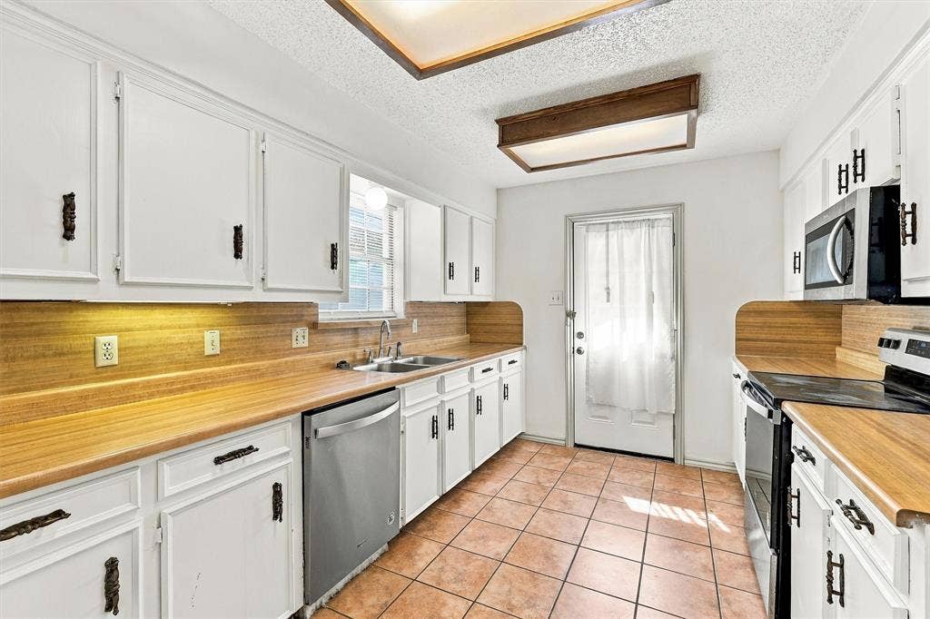 2145 Willow Place, #A, Carrollton, TX 75006 Kitchen featuring white shaker-style cabinetry, wood-finish countertops with matching backsplashes, ceramic tile flooring, and stainless steel appliances