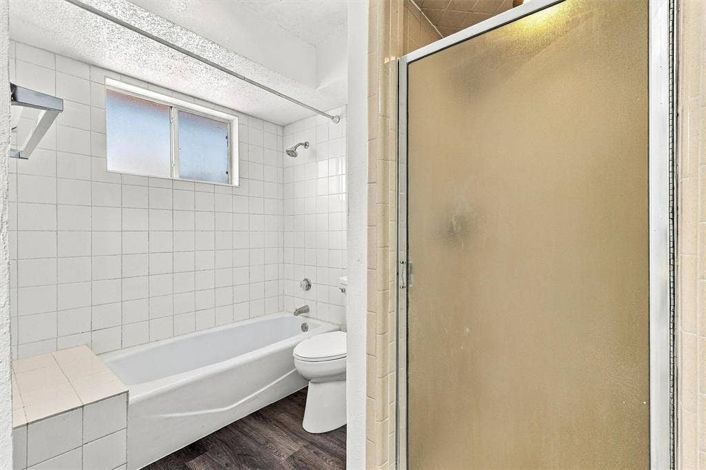2145 Willow Place, #A, Carrollton, TX 75006 Bathroom featuring a built-in bathtub with a tile surround, separate shower enclosure with a glass door, wood-finish flooring, and a window