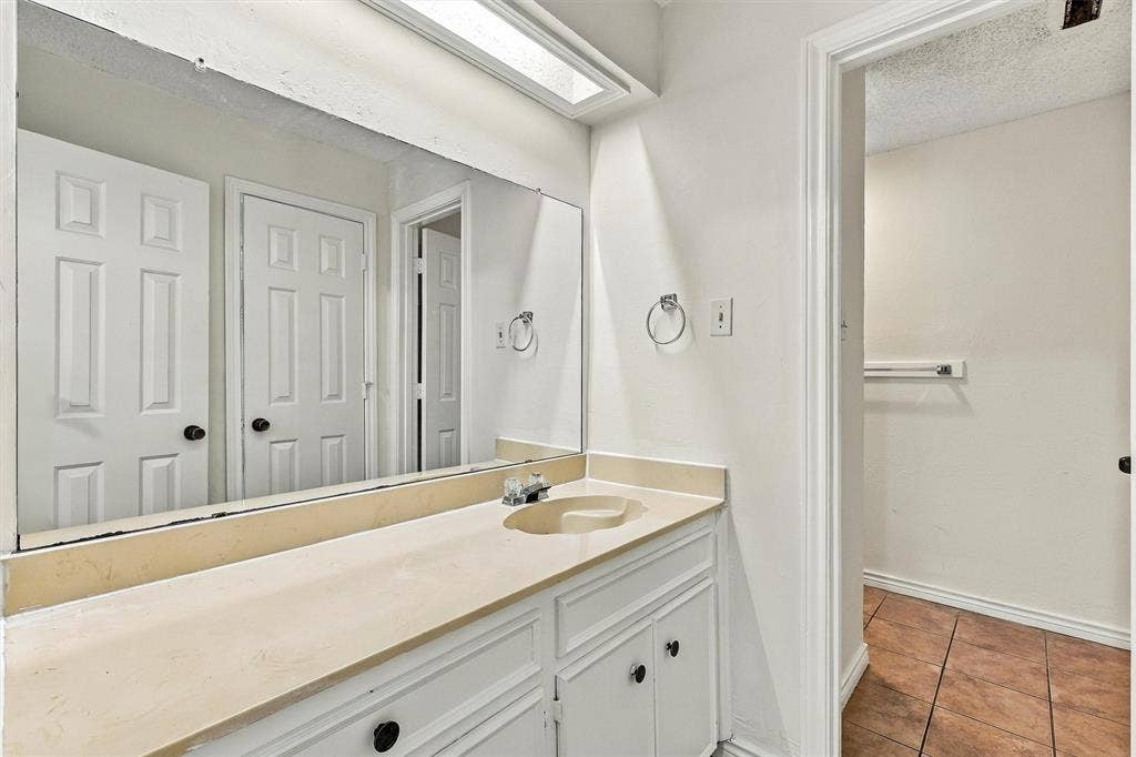 2145 Willow Place, #A, Carrollton, TX 75006 Built-in vanity with solid-surface countertop and integrated sink, full-width wall mirror, recessed overhead lighting, and tiled flooring
