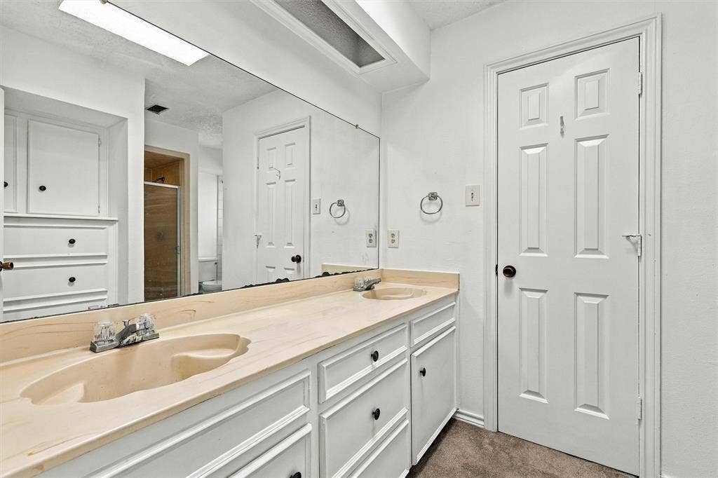 2145 Willow Place, #A, Carrollton, TX 75006 Dual-basin vanity featuring integrated sinks, expansive wall-to-wall mirror, extensive white built-in cabinetry, and recessed lighting