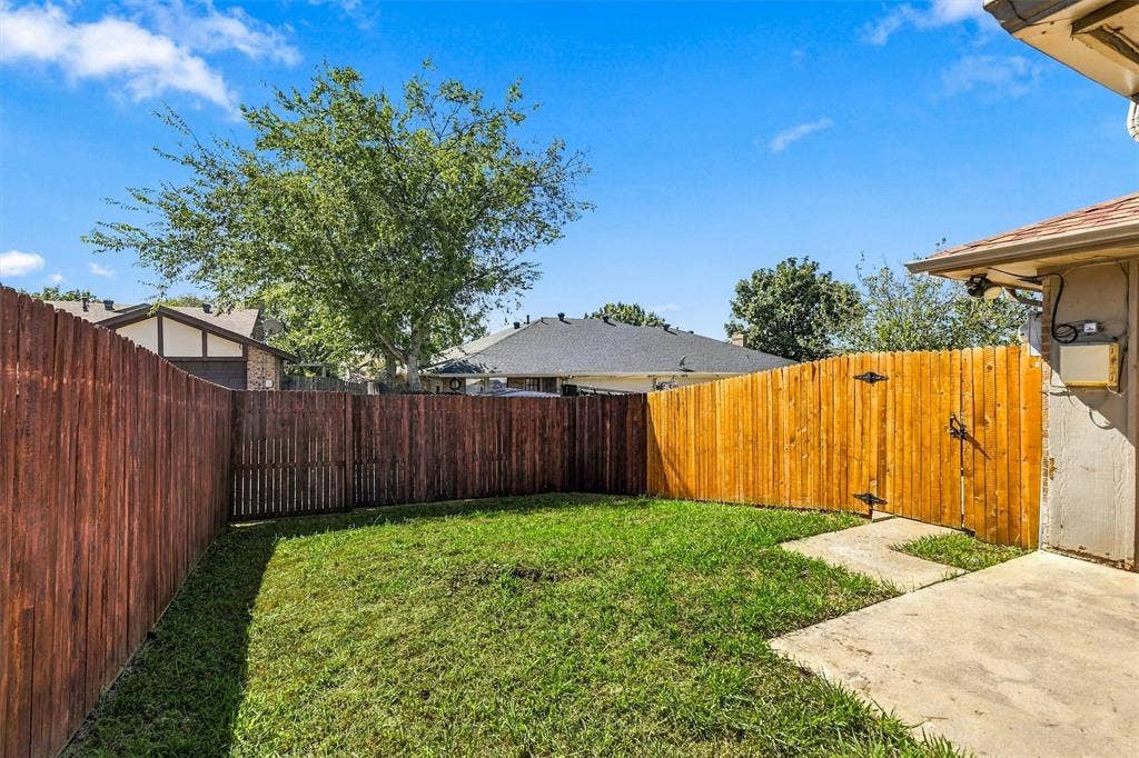 2145 Willow Place, #A, Carrollton, TX 75006 Fenced backyard featuring a grass lawn, concrete patio, and mature trees