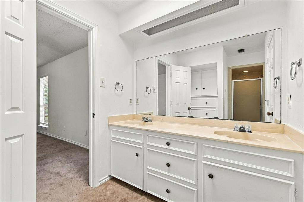 2145 Willow Place, #A, Carrollton, TX 75006 Dual-basin vanity featuring white cabinetry, integrated surface-mounted sinks, a full-width wall mirror, and recessed ceiling lighting