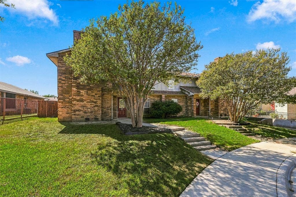 2145 Willow Place, #A, Carrollton, TX 75006 Multi-level brick exterior featuring concrete stairs, mature landscape trees, and a concrete walkway