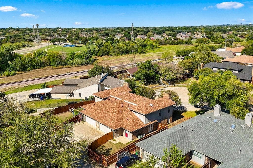2145 Willow Place, #A, Carrollton, TX 75006 Aerial perspective featuring a multi-level residence with a multi-gabled shingle roof, attached garage, and a fenced backyard