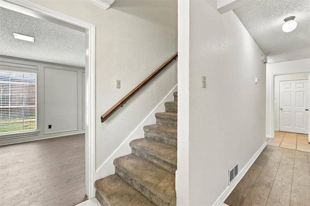2145 Willow Place, #A, Carrollton, TX 75006 Carpeted staircase with a wood handrail, wood-finish flooring, paneled wall detailing, and a multi-panel door