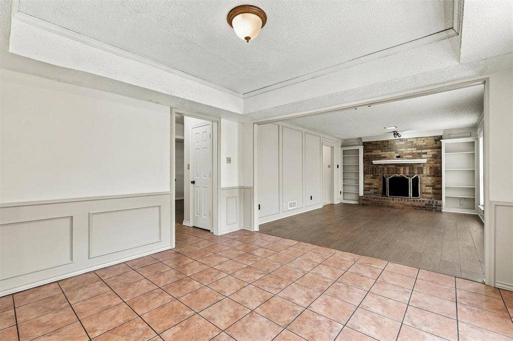 2145 Willow Place, #A, Carrollton, TX 75006 Interior featuring tray ceilings, wainscoting, tile flooring, wood-finish flooring, and a brick fireplace with built-in shelving