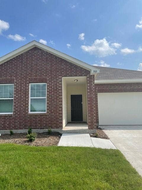 Single-story exterior featuring a brick facade, concrete driveway, recessed entryway, and a multi-panel door