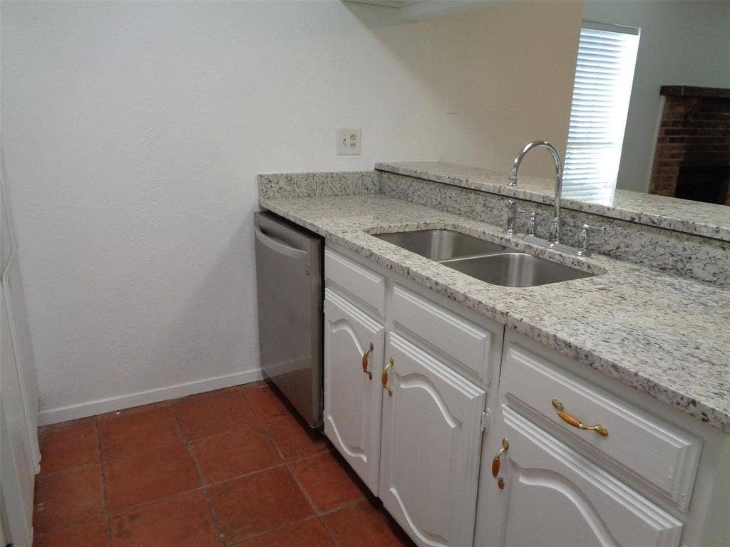 909 Turtle Cove, #141, Irving, TX 75060 Kitchen featuring stone countertops, white cabinetry with metallic hardware, a stainless steel dishwasher, a double-basin stainless steel sink with a high-arch faucet, and terracotta-toned floor tiling