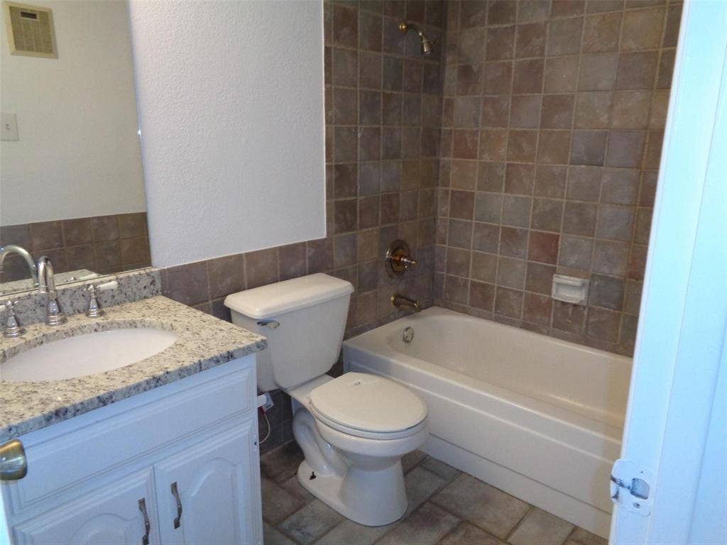 909 Turtle Cove, #141, Irving, TX 75060 Bathroom featuring a vanity with a light-toned stone countertop, an integrated sink, a deep soaking tub with a tiled surround, and ceramic tile flooring
