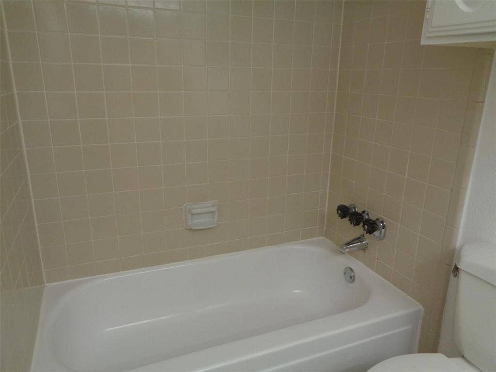 909 Turtle Cove, #141, Irving, TX 75060 Full-size soaking tub featuring a neutral-toned square tile surround, integrated soap dish, and chrome-finish plumbing fixtures