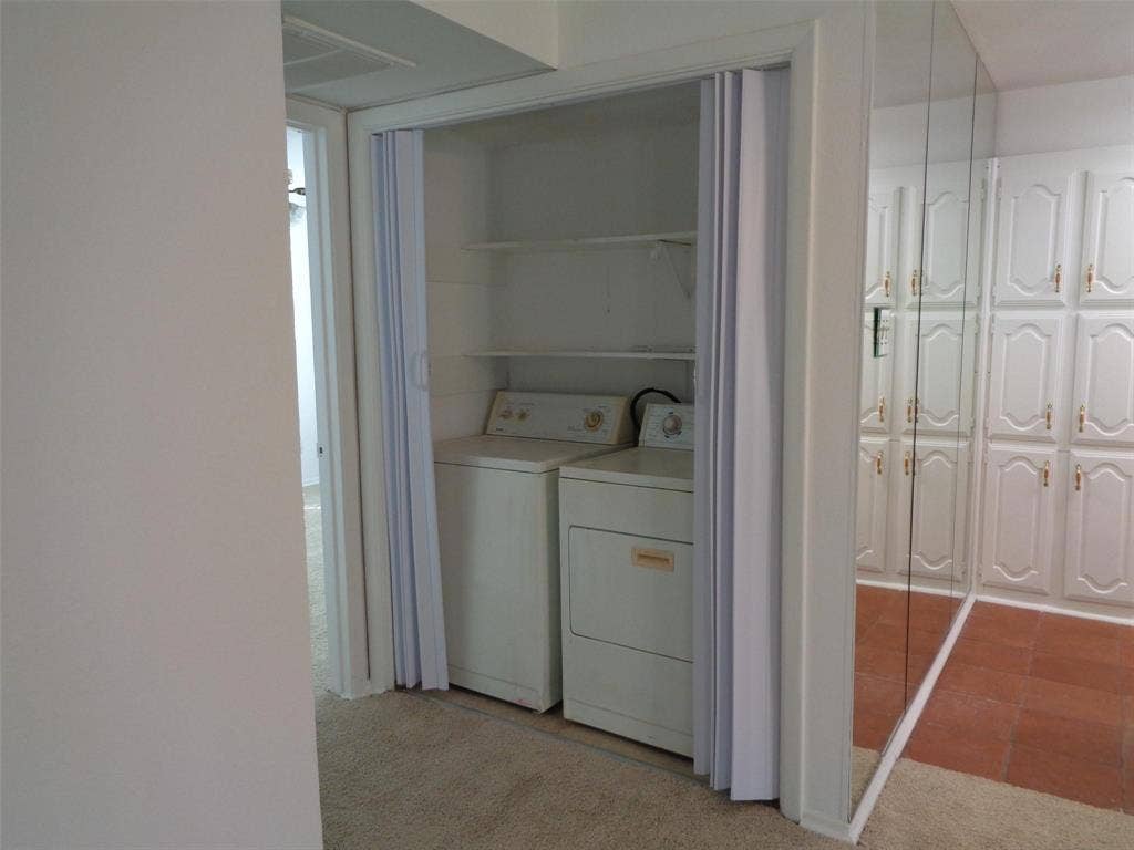 909 Turtle Cove, #141, Irving, TX 75060 Laundry closet featuring folding privacy doors and built-in shelving, complemented by floor-to-ceiling mirrored closet doors with paneled detailing