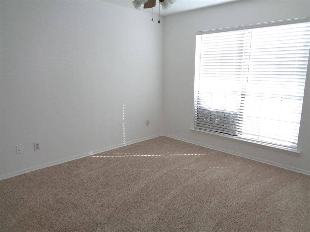 909 Turtle Cove, #141, Irving, TX 75060 Neutral-toned carpeting, large window with integrated blinds, and ceiling fan with integrated light fixture