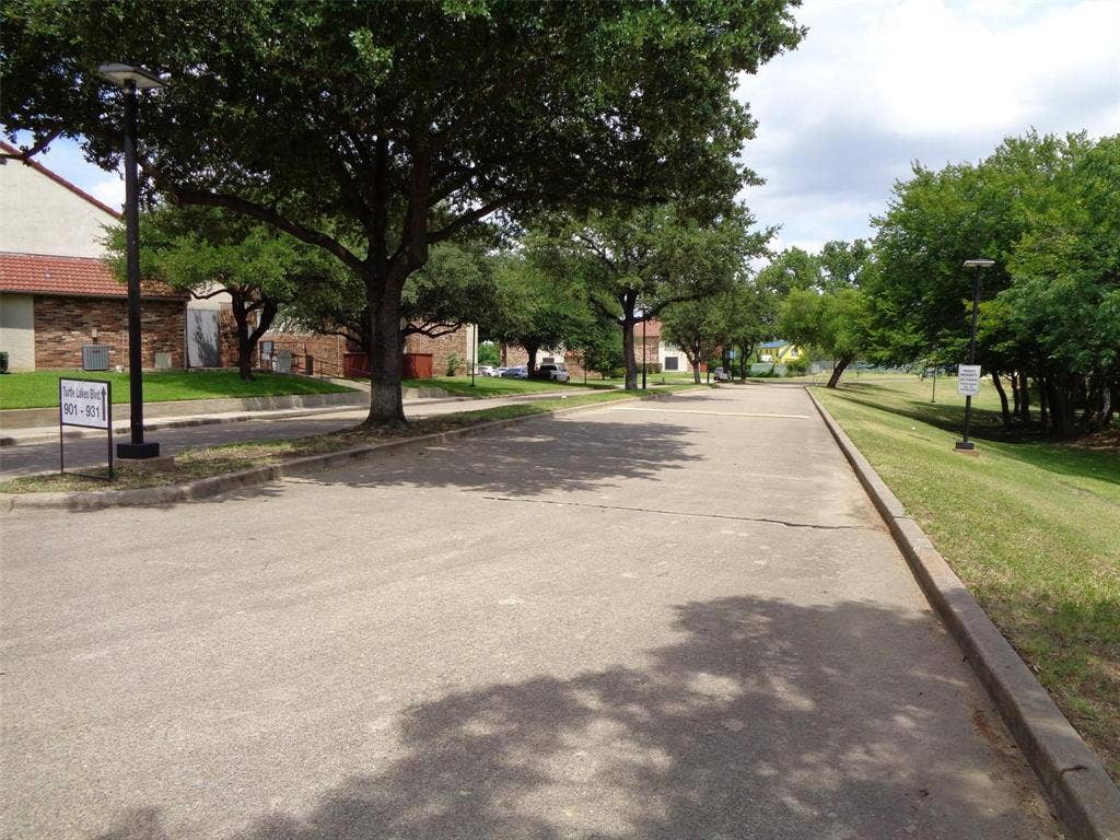 909 Turtle Cove, #141, Irving, TX 75060 Concrete paved drive featuring curb-lined edges, manicured grass embankments, mature trees, and installed exterior post lighting