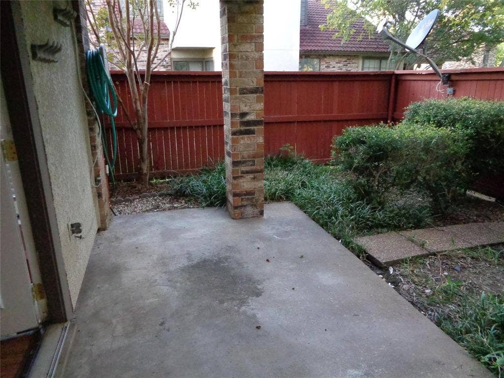 909 Turtle Cove, #141, Irving, TX 75060 Concrete patio featuring a brick support column, enclosed by a wood privacy fence and landscaped with shrubbery