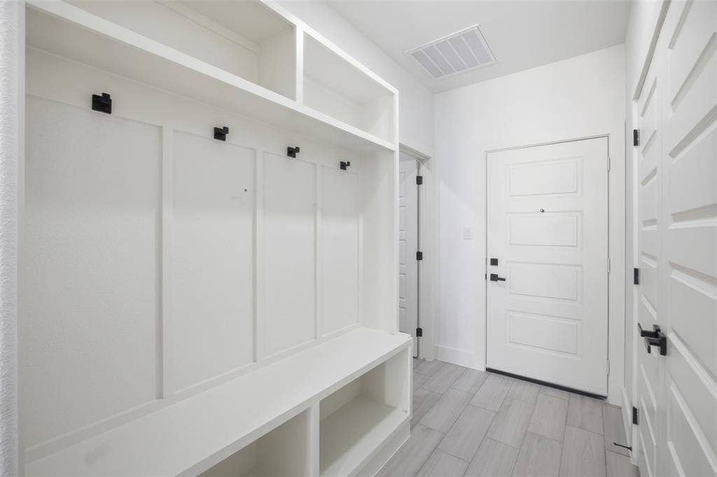 101 Connor Circle, Mabank, TX 75147 Built-in white storage cabinetry featuring upper shelving, integrated bench seating, and matte black hardware, accented by light-toned plank flooring and a four-panel door with matte black lever handles