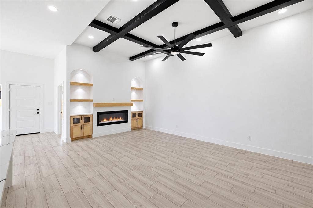 101 Connor Circle, Mabank, TX 75147 Living area featuring high ceilings with a dark-finished coffered beam design, wood-finish flooring, a contemporary electric fireplace with a wood mantel, and built-in recessed shelving