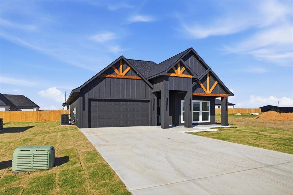 101 Connor Circle, Mabank, TX 75147 Single-story exterior featuring dark vertical siding, contrasting wood-finish gables, a concrete driveway, and an attached two-car garage