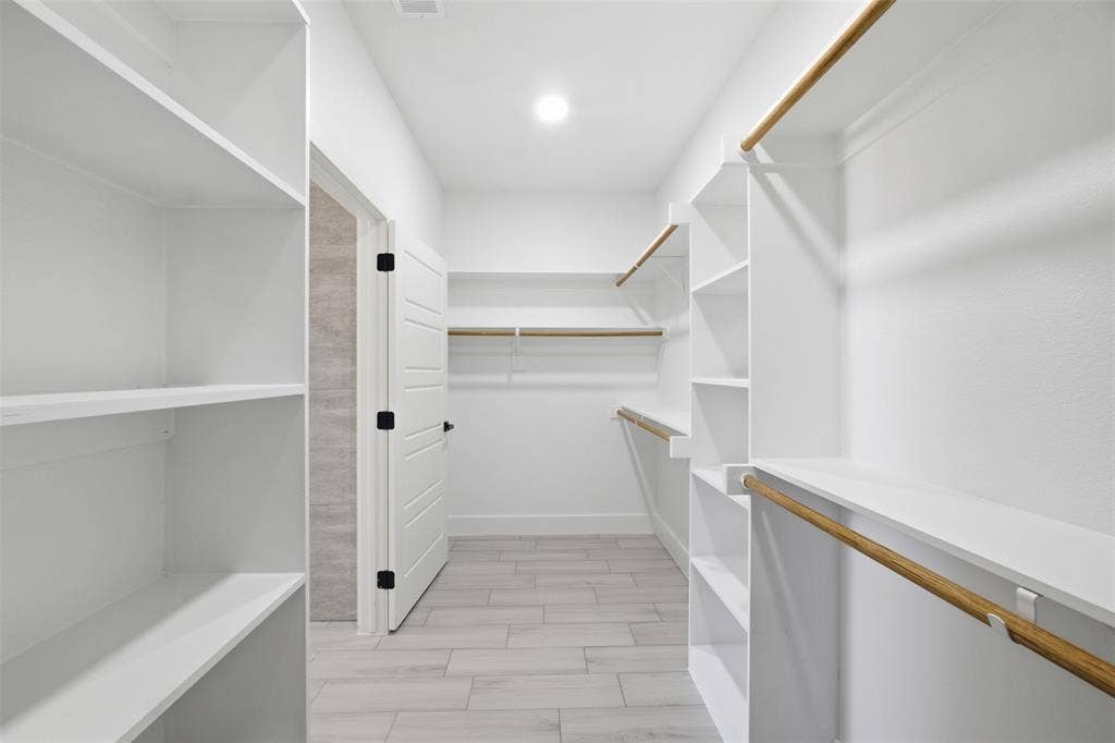 101 Connor Circle, Mabank, TX 75147 Walk-in closet featuring white built-in shelving, wooden garment rods, tile flooring, and a multi-panel door with black hardware