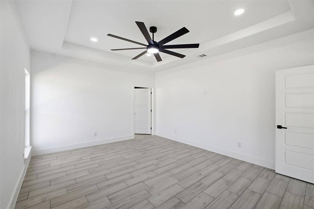 101 Connor Circle, Mabank, TX 75147 Tray ceiling featuring a multi-blade matte black ceiling fan, wood-finish flooring, recessed lighting, and five-panel interior doors with matte black hardware
